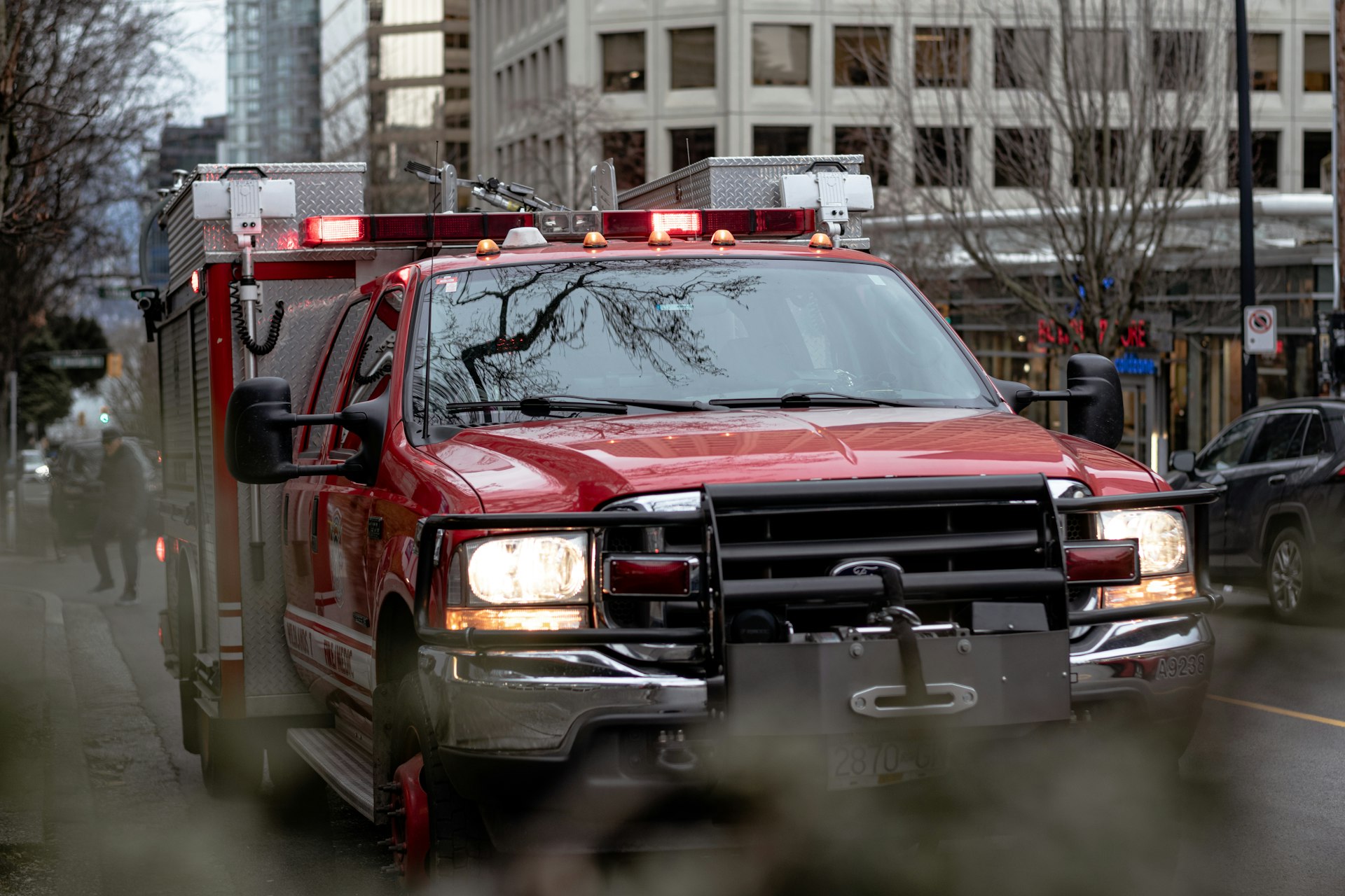 a red fire truck driving down a street next to tall buildings